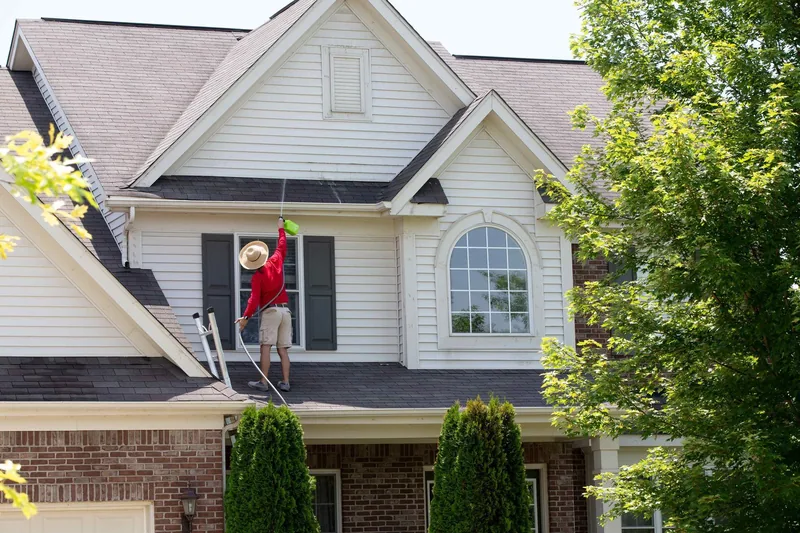 man pressure washing a house